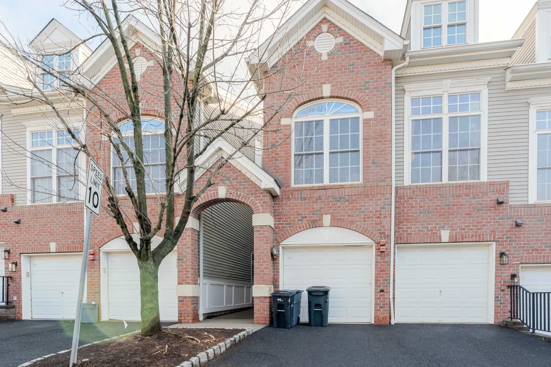 A brick townhouse in a Scotch Plains development, with attached garages at street level